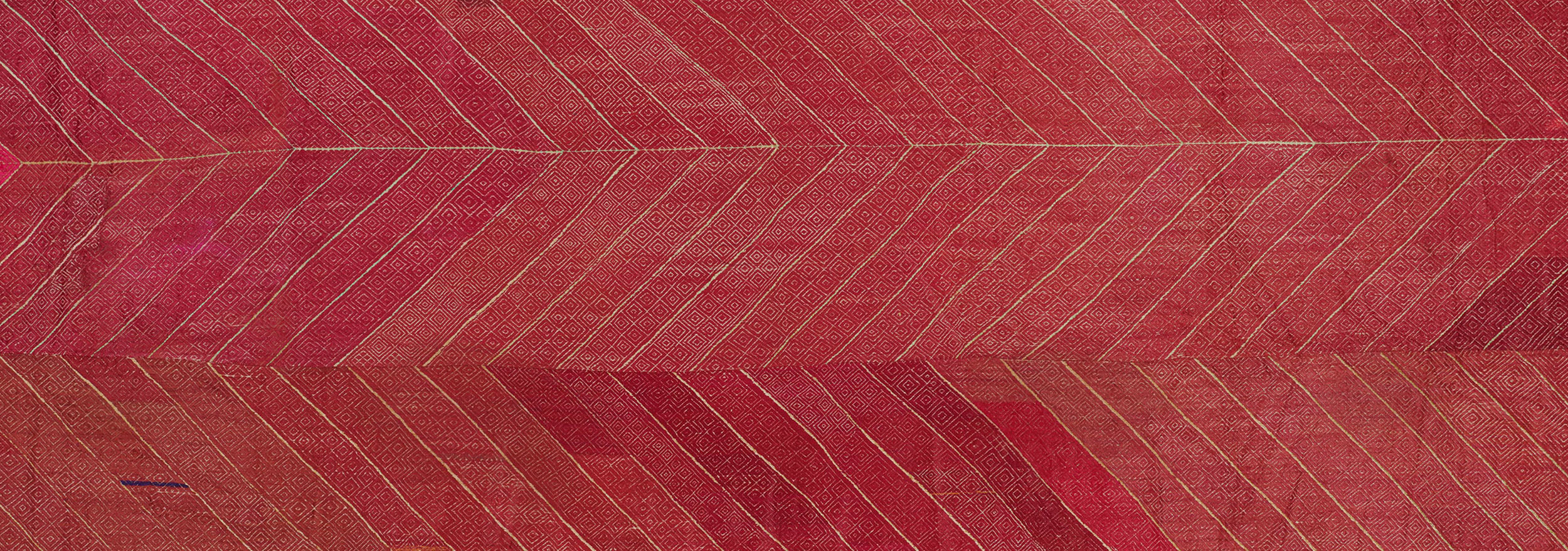 A Bagh Phulkari textile with three alternating rows of diagonal patterns filled with square motifs.