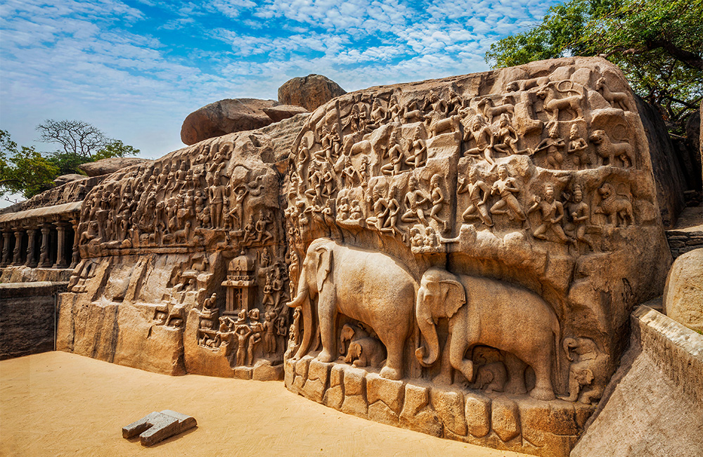 A photograph of two intricately carved rock monoliths depicting humans figures, gods, mythical creatures and animals.