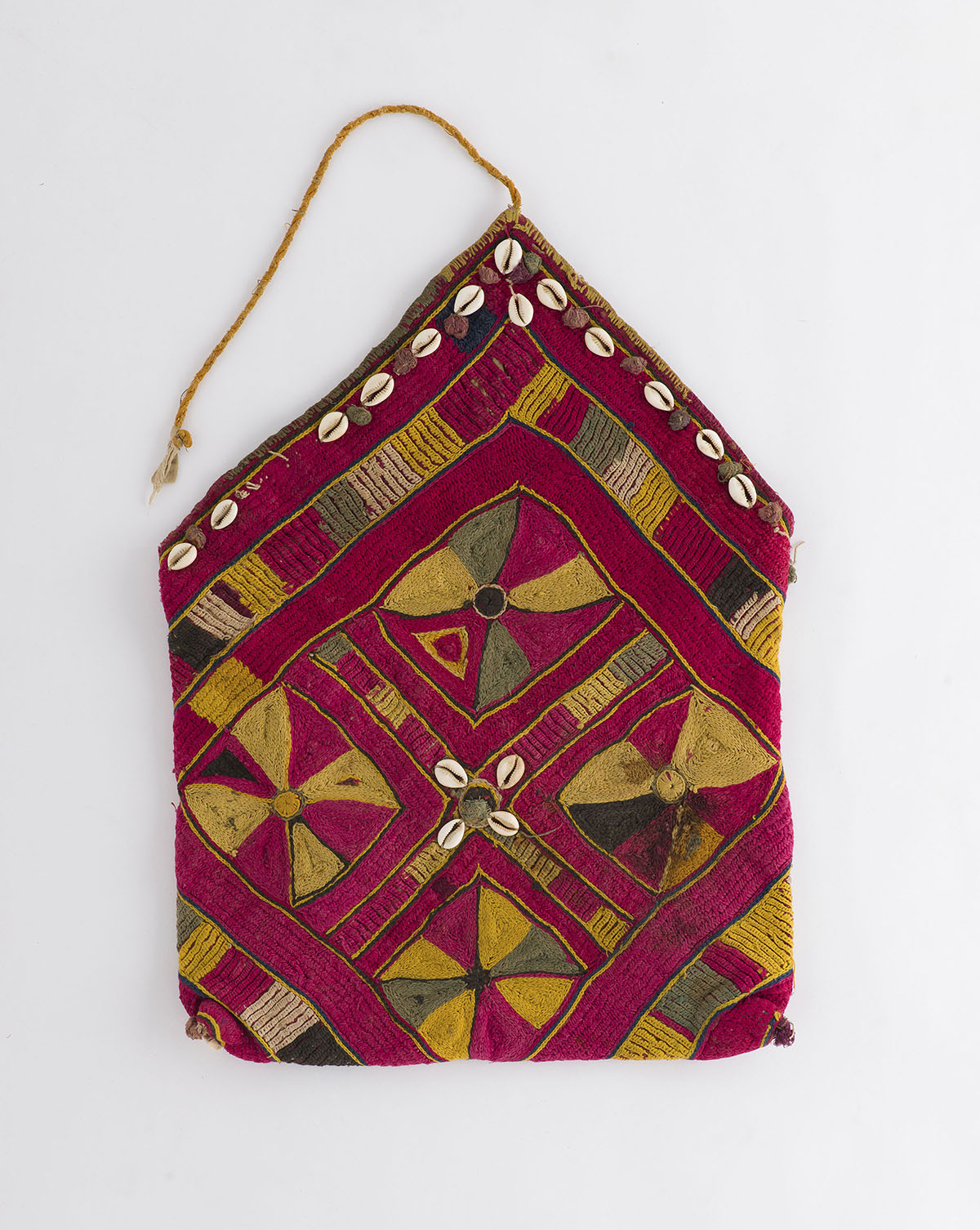 A vividly coloured handwoven bag, with Banjara embroidery and cowry shells decorating its upper edge.