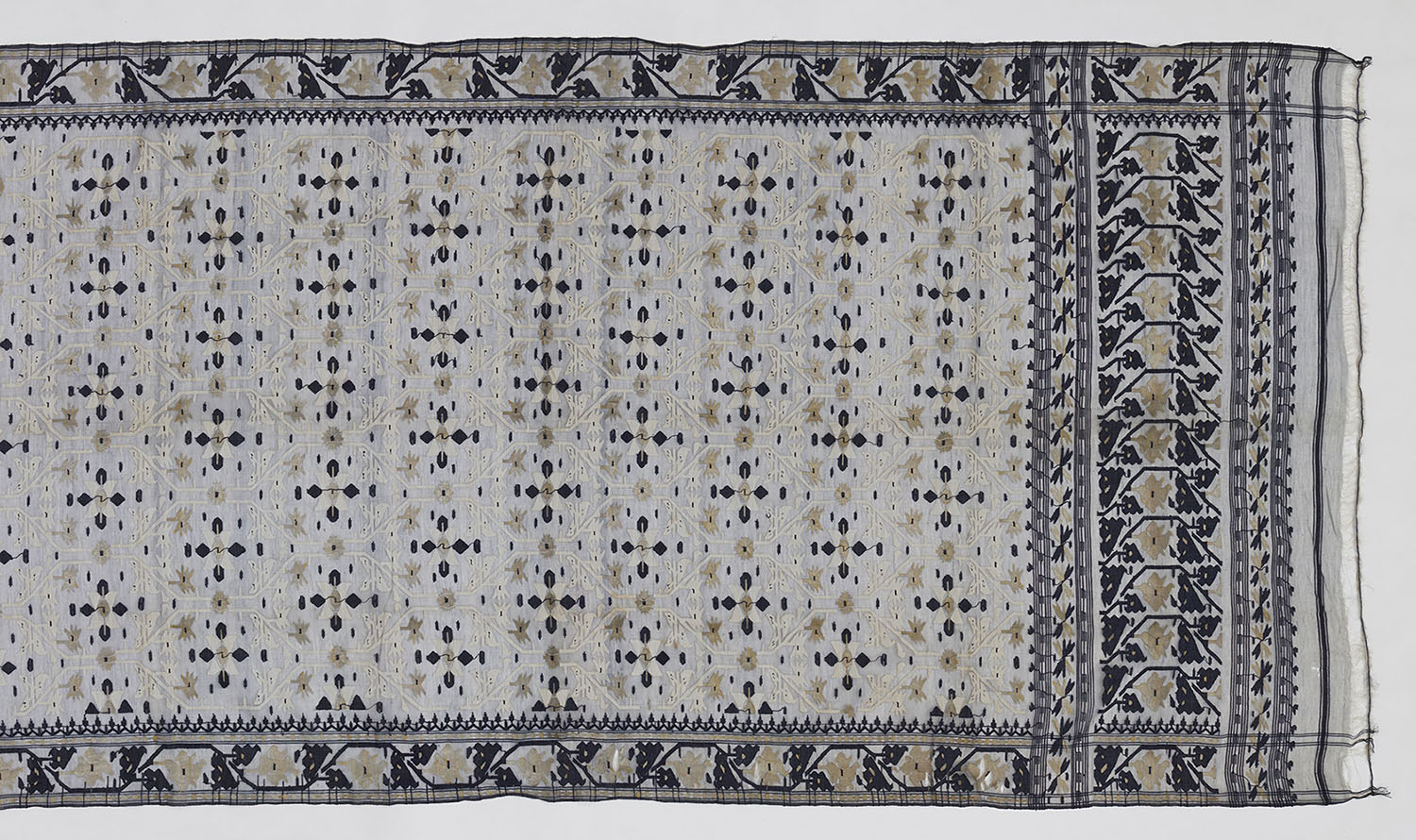 A Jamdani saree with floral motifs in diamond-shaped cells in the centre, and a dense border of similar motifs.
