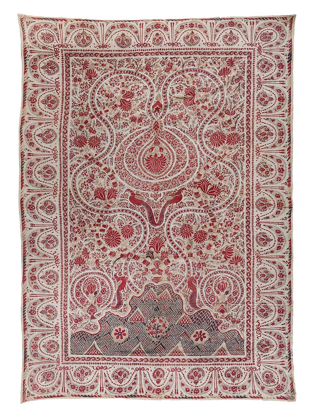 A Palampore textile with a mirrored pattern of birds and floral motifs at the centre and a festoon design on the border.