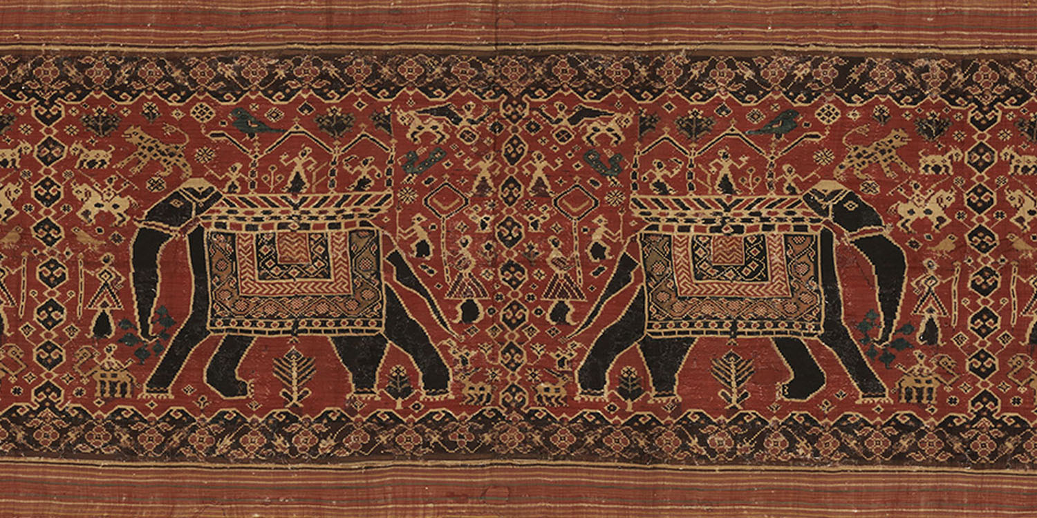 A Patan Patola textile with a pattern of two pairs of elephants on the body and floral and triangle motifs on the border.