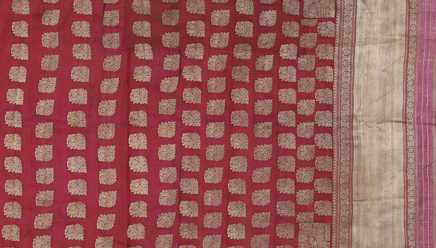 A saree heavily brocaded in gold with a scattered buta motif covering its length.
