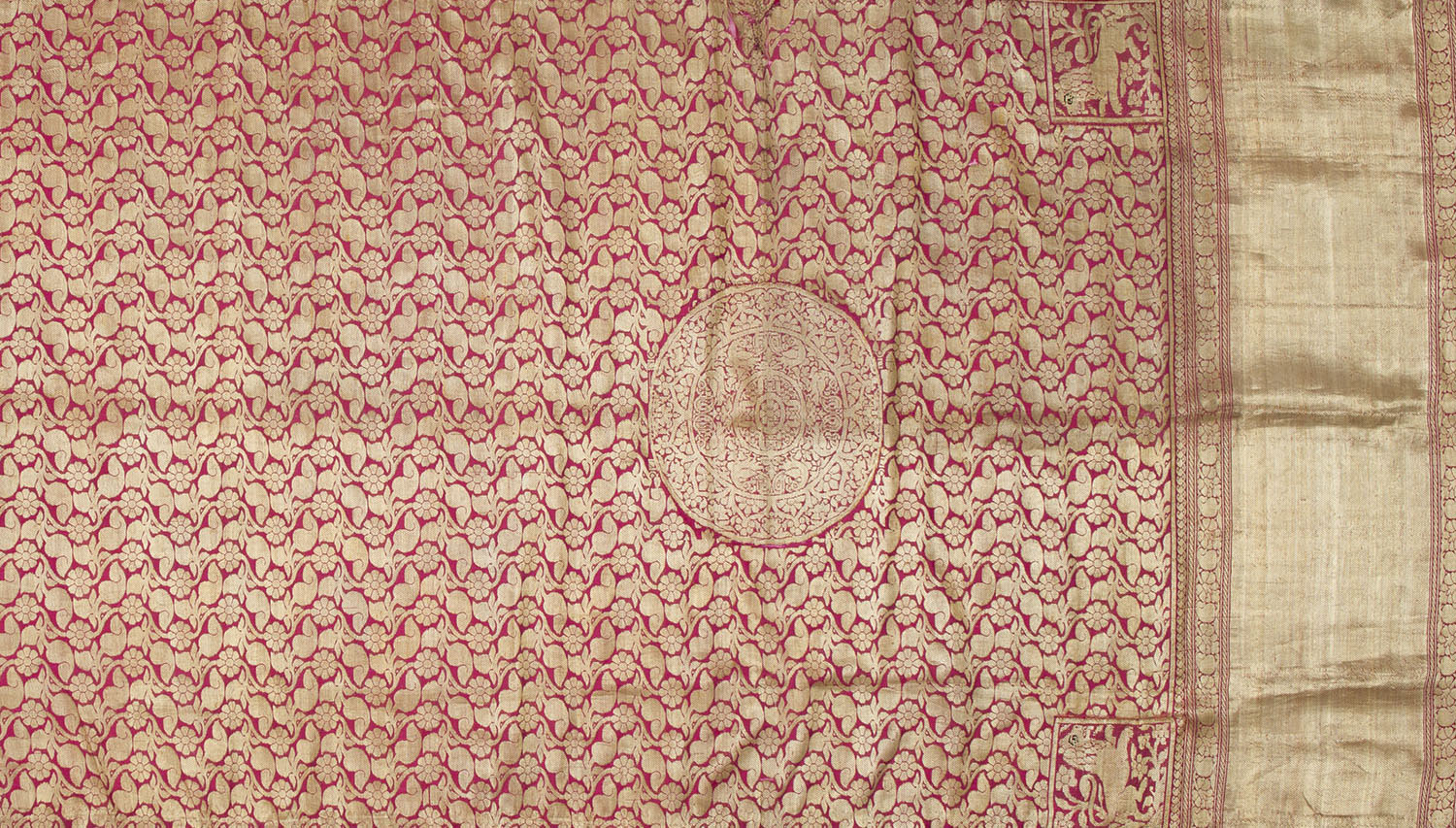 A saree heavily brocaded in gold with a jaali or trellis pattern that covers its length and a large medallion towards the border.