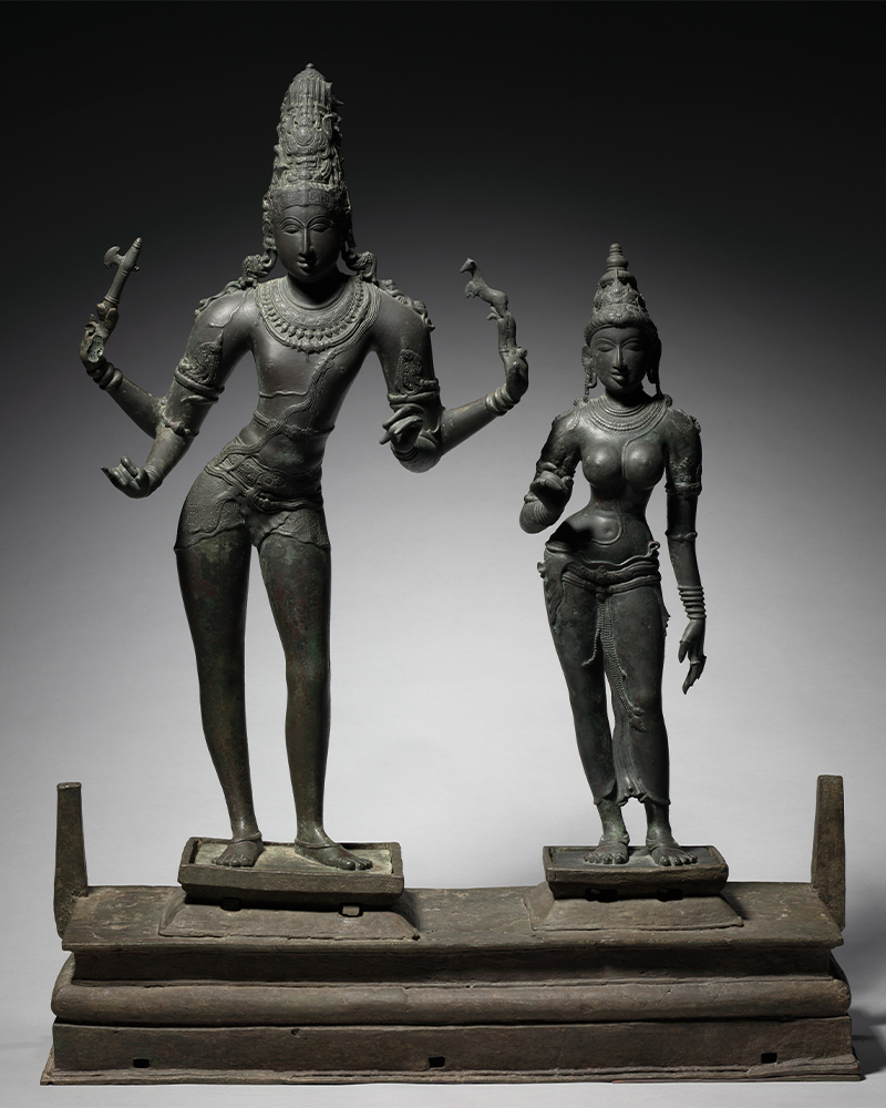 Two bronze statues depicting Shiva standing on the left and Parvati on the right.