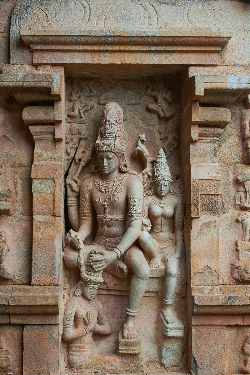 A relief depicting Shiva on the left, wrapping a flower garland around Chandesa and accompanied by Parvati on the right.
