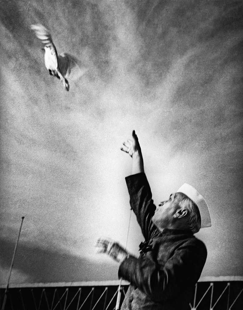 A black and white photograph of Jawaharlal Nehru releasing a dove to the sky.