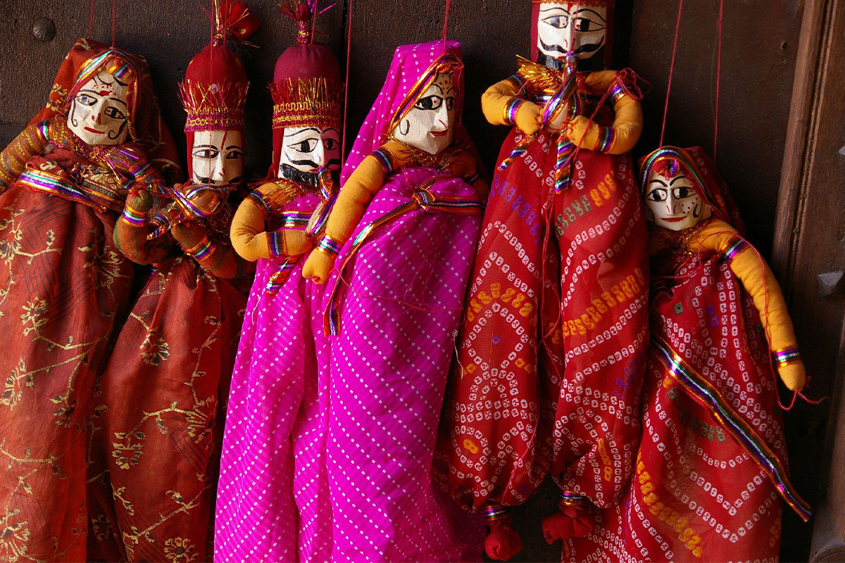 A set of six Rajasthani string puppets, depicting male and female characters, in flowing costumes.