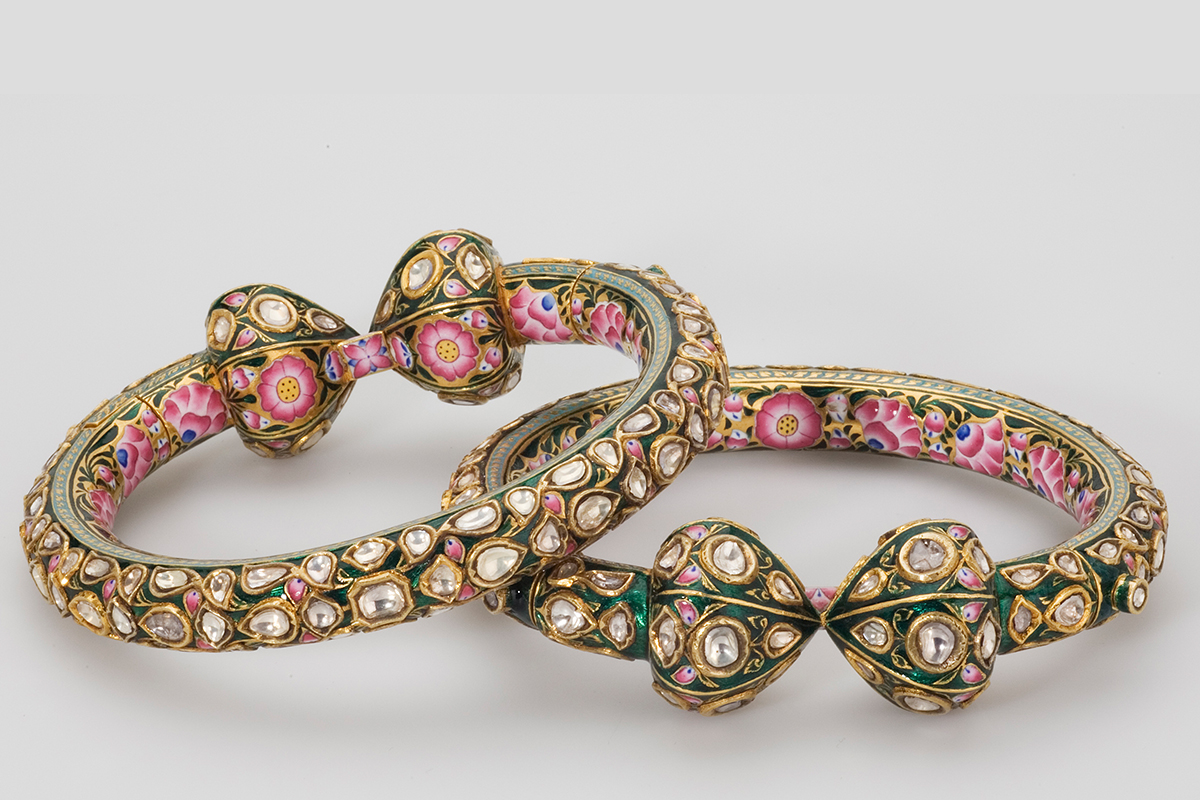 Two circular anklets with kundan work on the outside and painted floral designs on the inside.