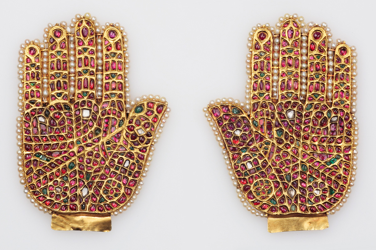 A pair of hands made of gold, studded with precious stones and outlined by a row of pearls along the edges.