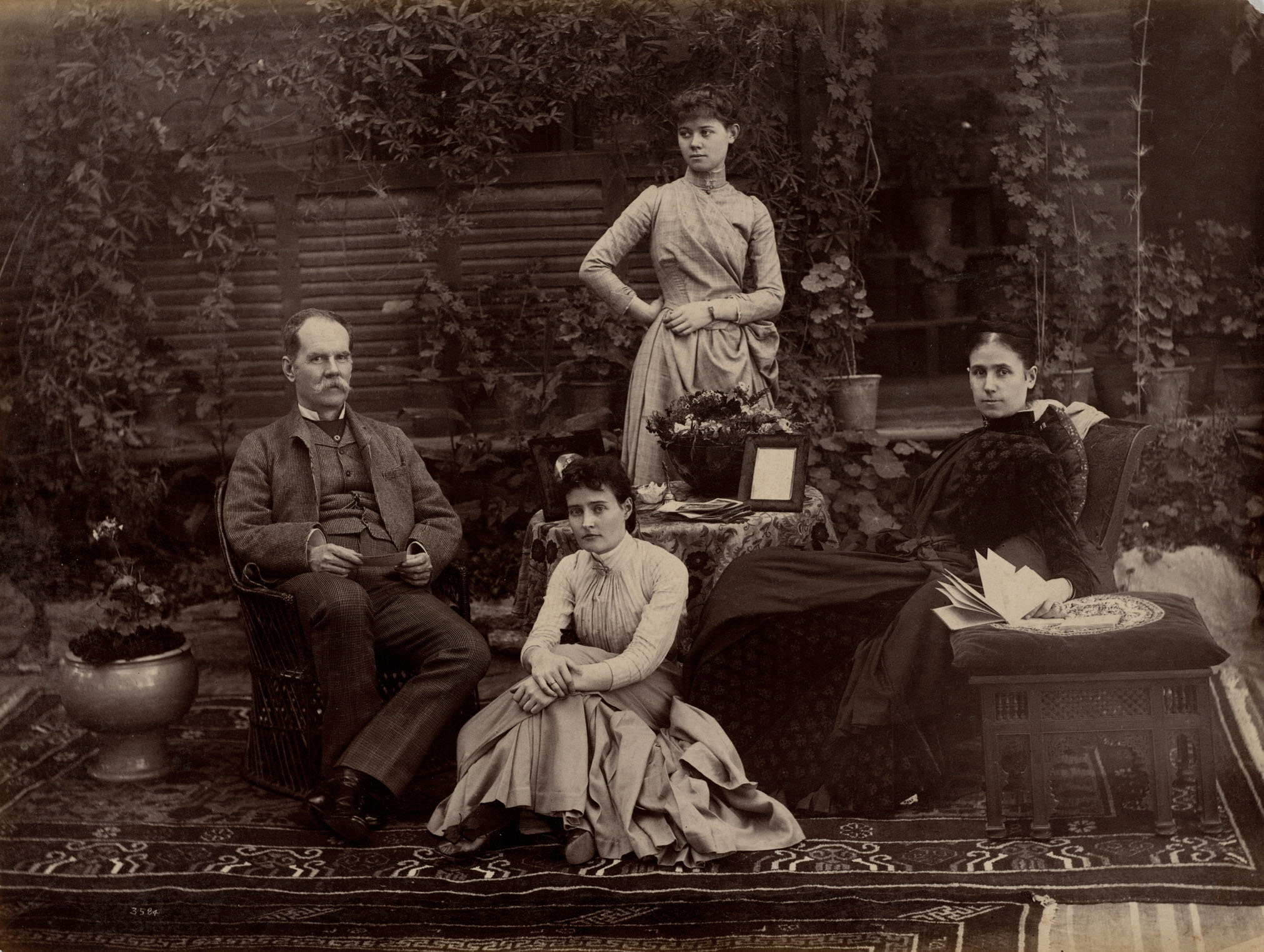 A sepia-toned photograph of the colonial administrator Auckland Colvin with his wife and two daughters seated in a garden.