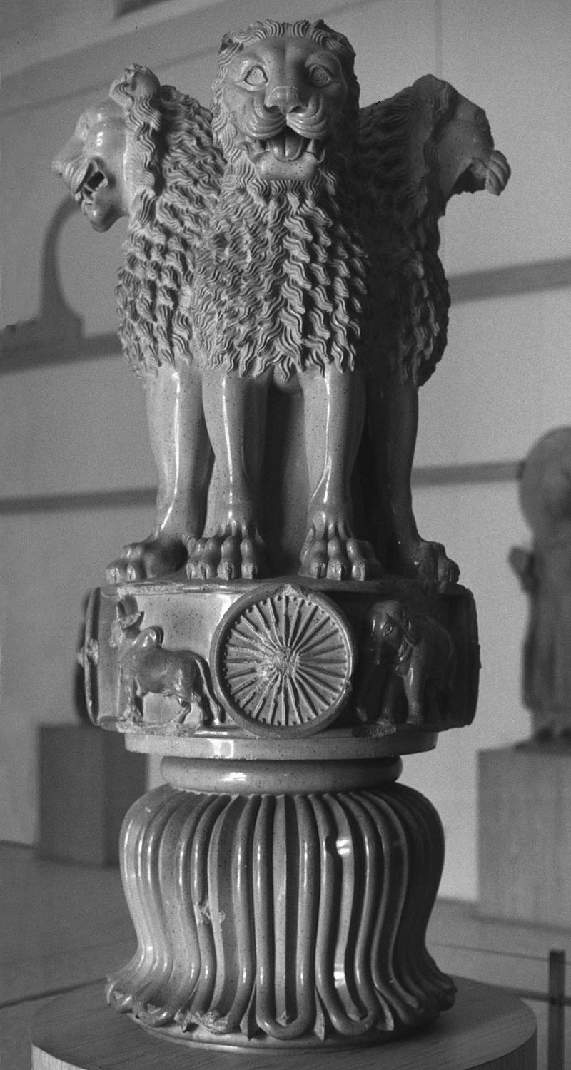 A sculptural capital depicting four lions standing on top of an Ashoka chakra and an inverted lotus.
