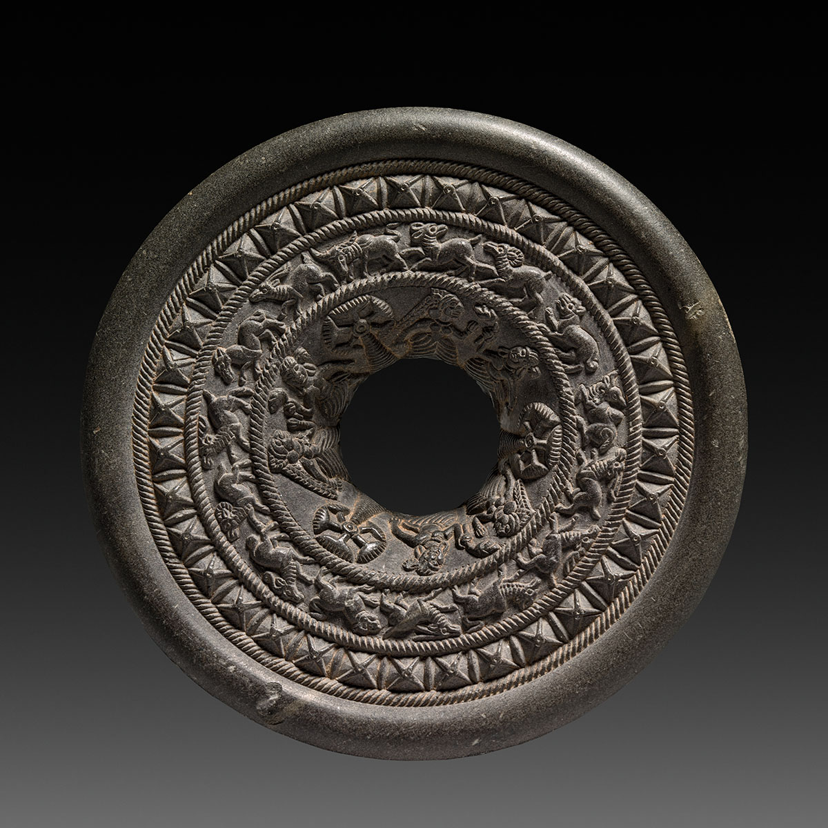 A stone ring engraved with goddesses, animals and geometric shapes tapering towards a hollow centre.