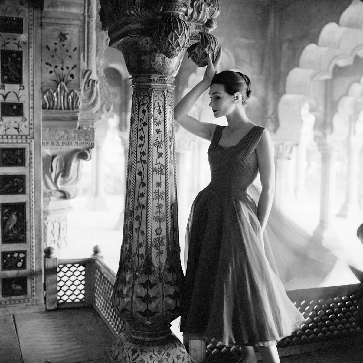 A photograph of a model in an evening dress standing by an inlaid column of the Red Fort in Delhi.