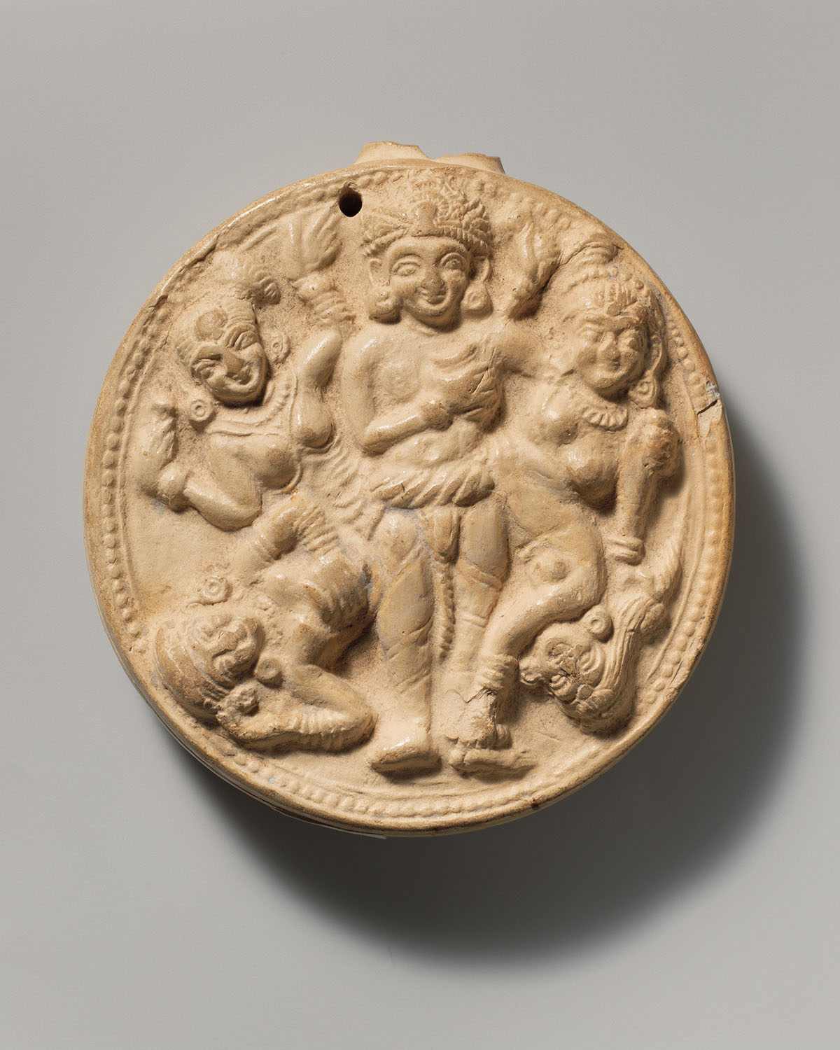A terracotta figurine holding a small child, accompanied by a parrot.