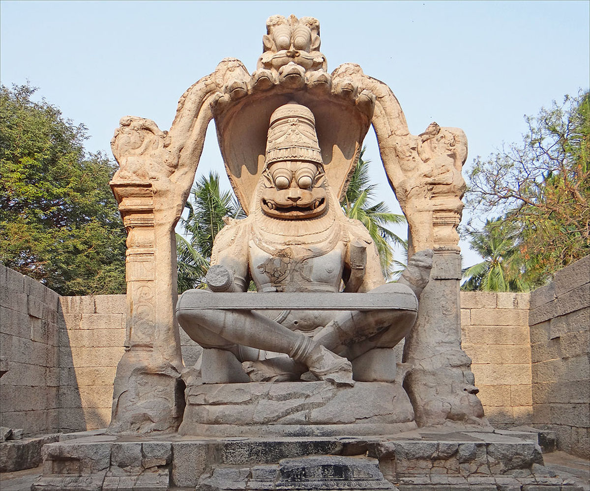 A statue depicting Narasimha sitting cross-legged, with an umbrella over his head.