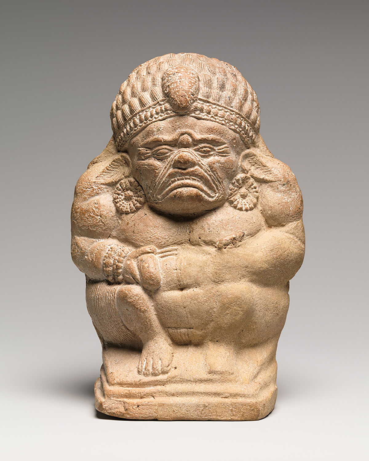 A figurine depicting a crouching figure with clasped hands and a sour expression.
