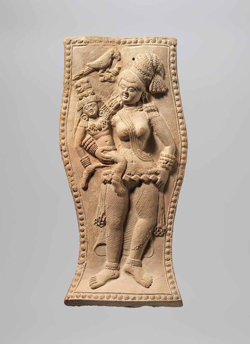 A terracotta figurine holding a small child, accompanied by a parrot.