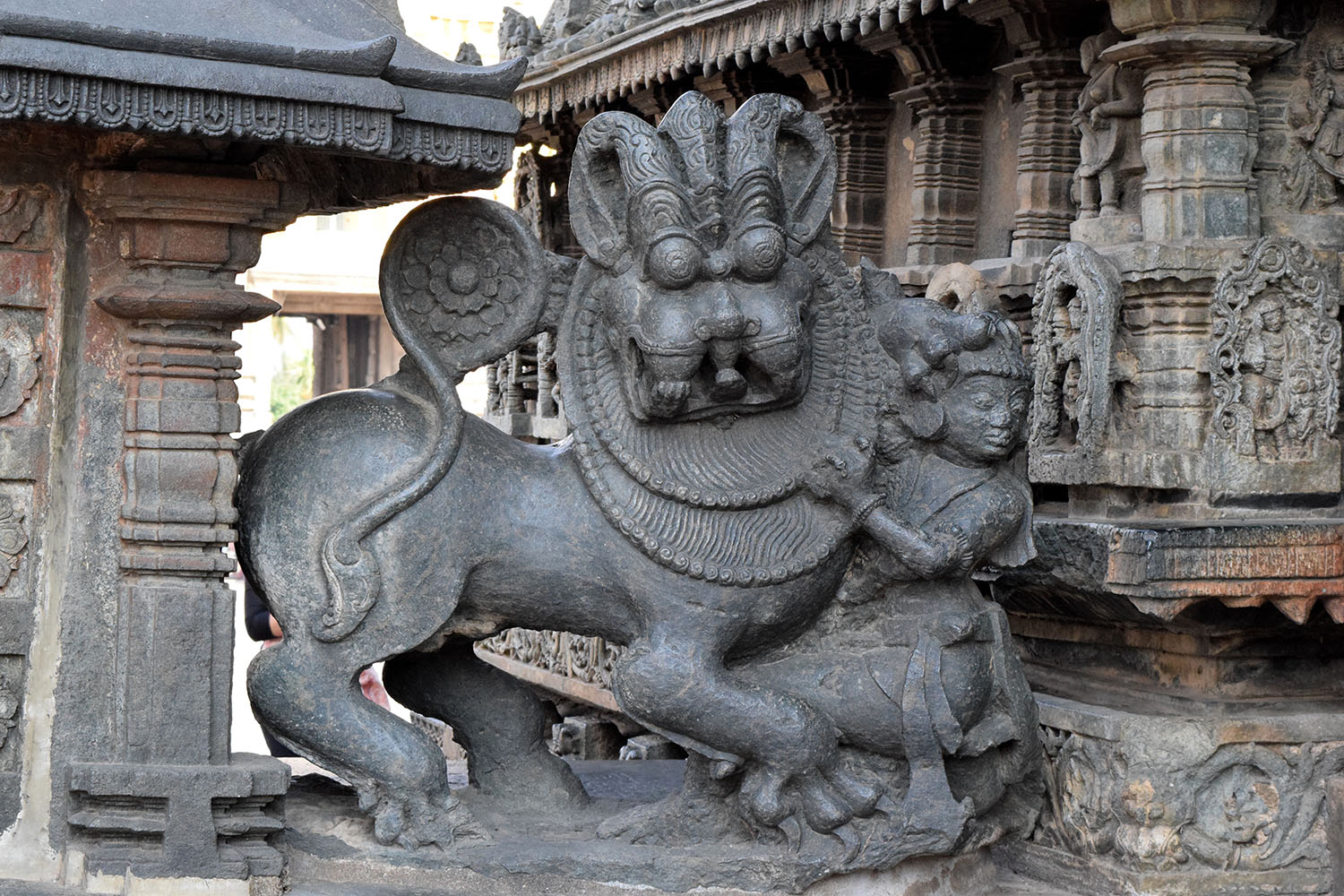 A statue of the mythical creature Yali, who is part lion, elephant and horse, accompanied by a woman seated next to it.