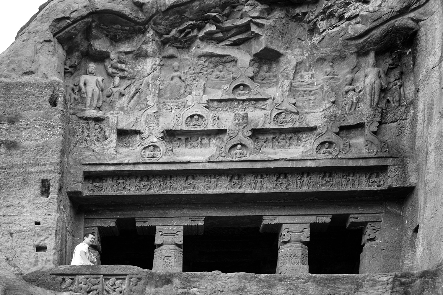 Photograph of the front facade of Ellora Cave 6 with relief carvings of Buddhas and other figures